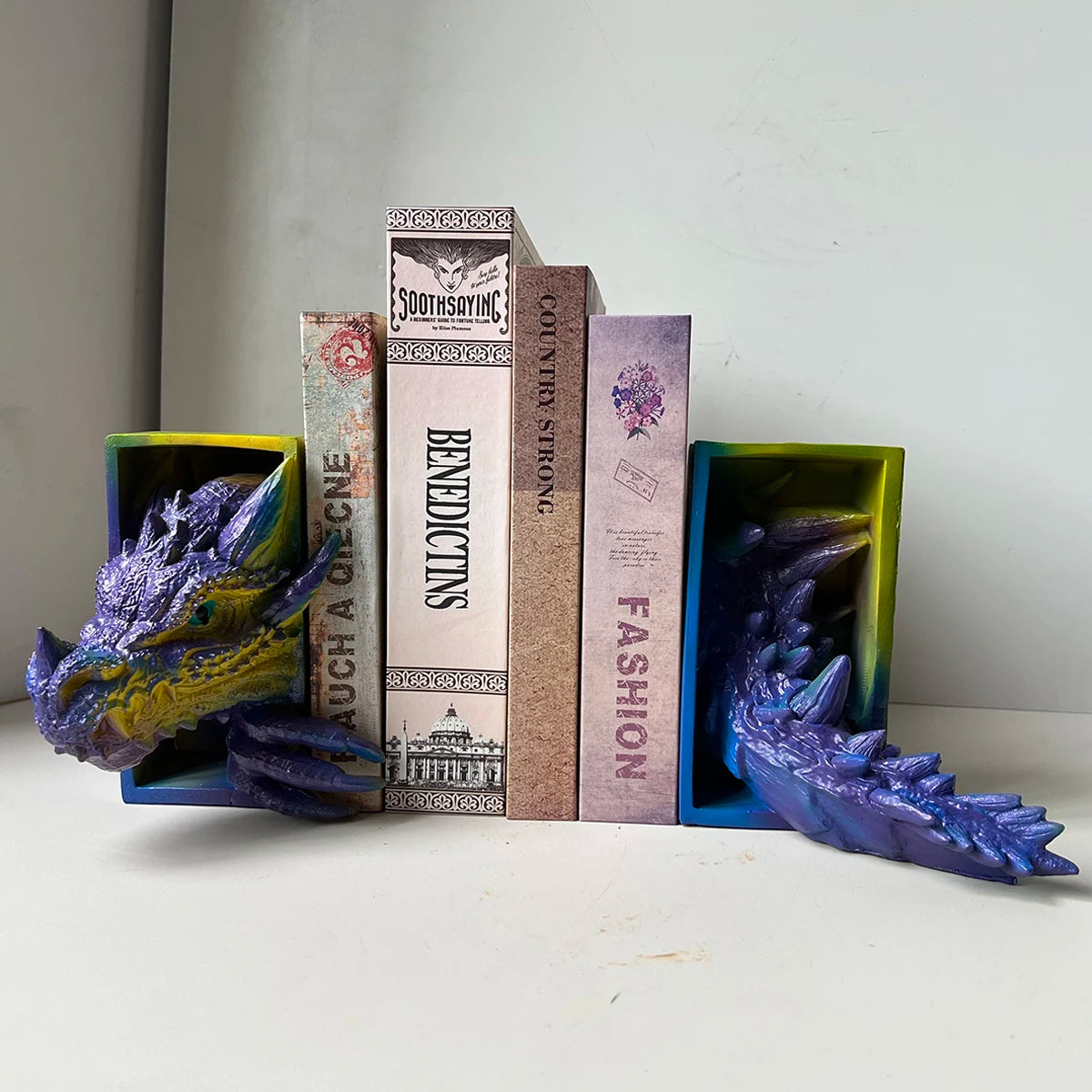 Multicolor dragon head and tail resin bookends holding books on a shelf