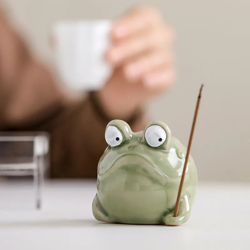 Frog-shaped ceramic incense holder on a tabletop in a living room setting