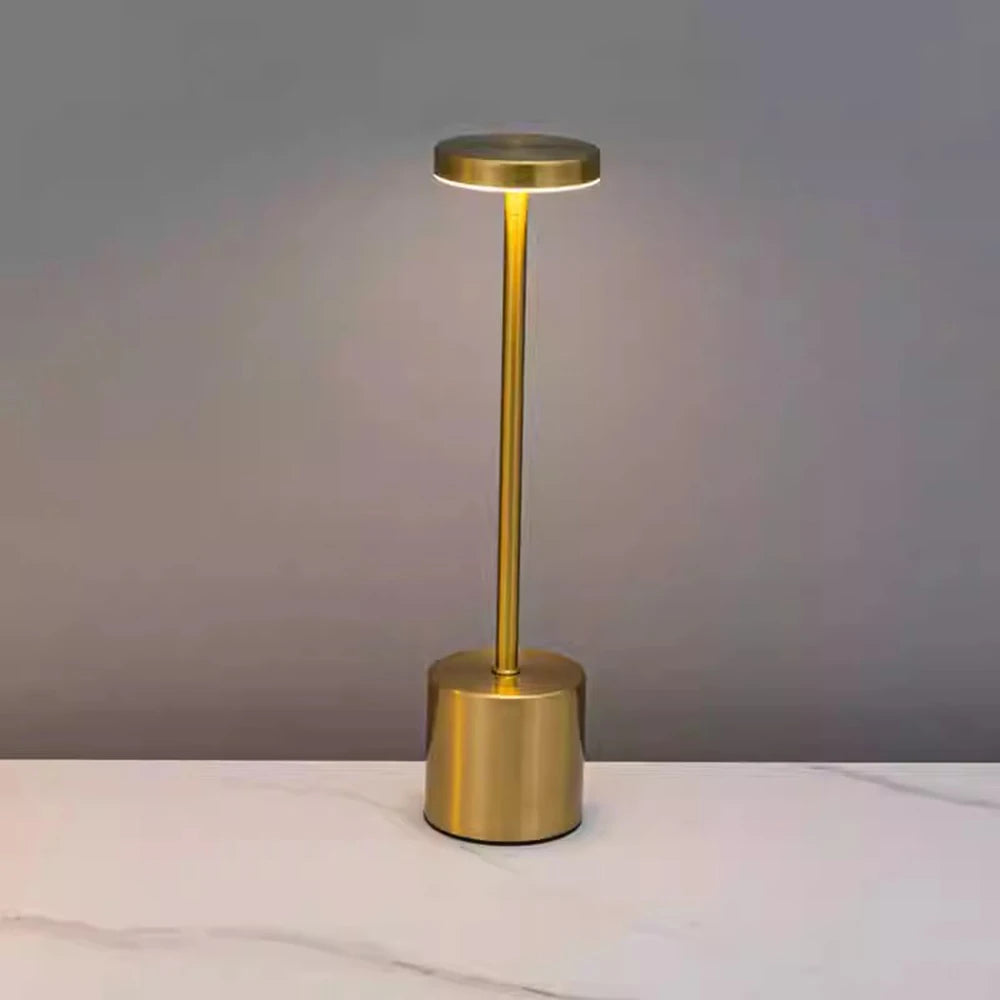 Gold cordless LED table lamp lit up on a marble top
