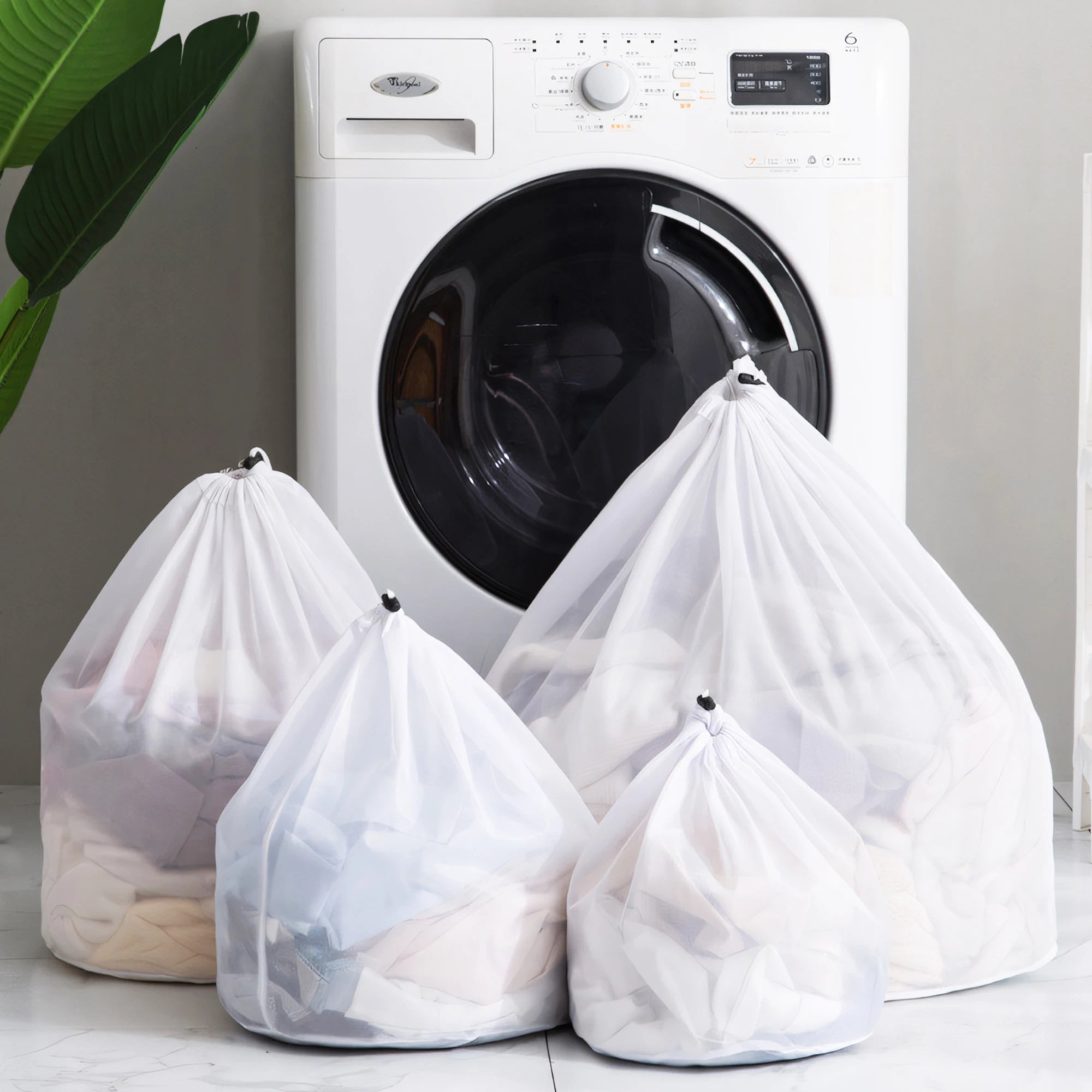 Four mesh laundry bags filled with clothes in front of a washing machine