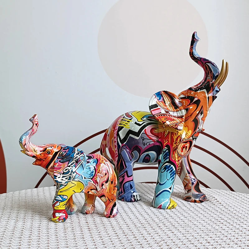 Two graffiti elephant sculptures in different sizes on a tabletop