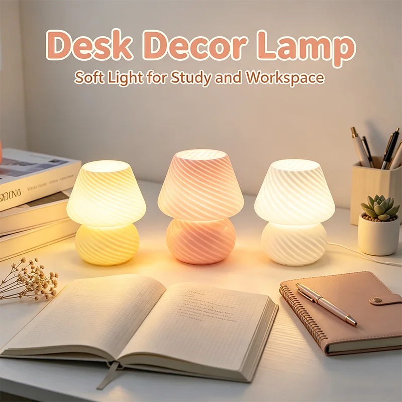 three mushroom-shaped glass table lamps in white and pink glowing softly on a desk with books and notebooks