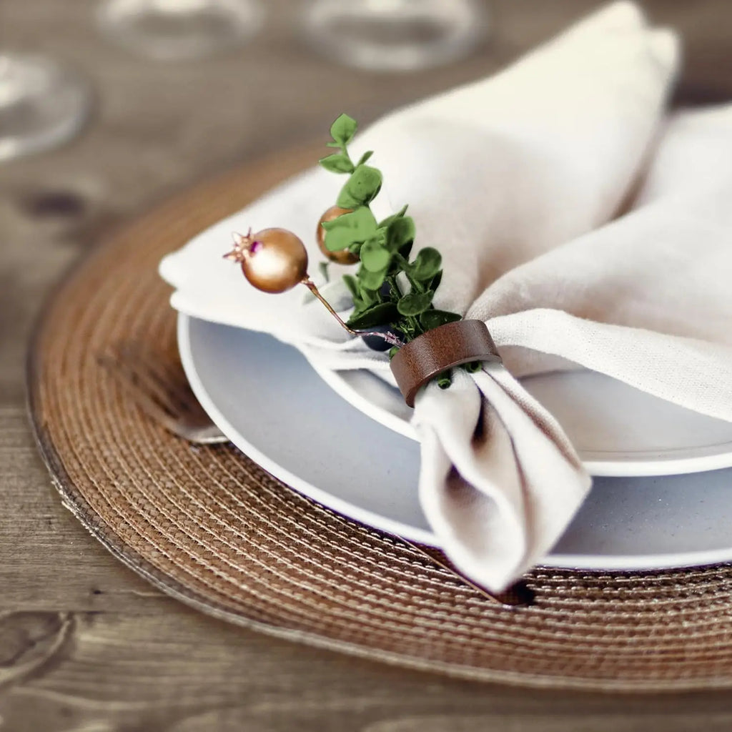 Wooden napkin ring with folded neutral napkin on a plate, styled with berries and greenery