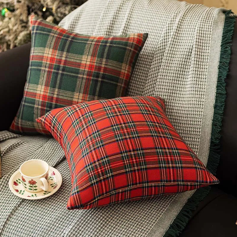 Green and red tartan plaid throw pillow covers on a grey blanket with a tea cup