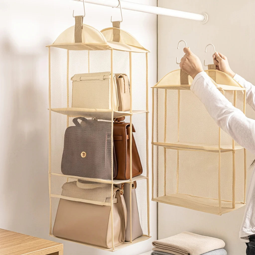Two beige hanging purse organizers side-by-side on closet rods, one being held and the other filled with handbags