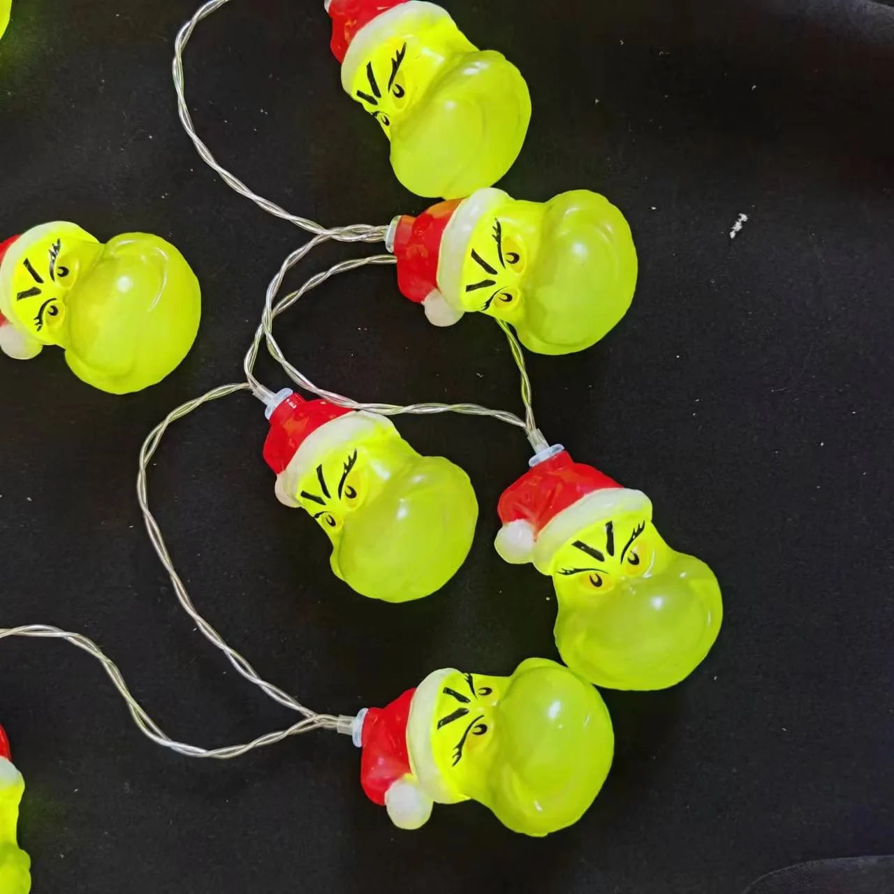 Close-up of Grinch character Christmas string lights laid out on a surface