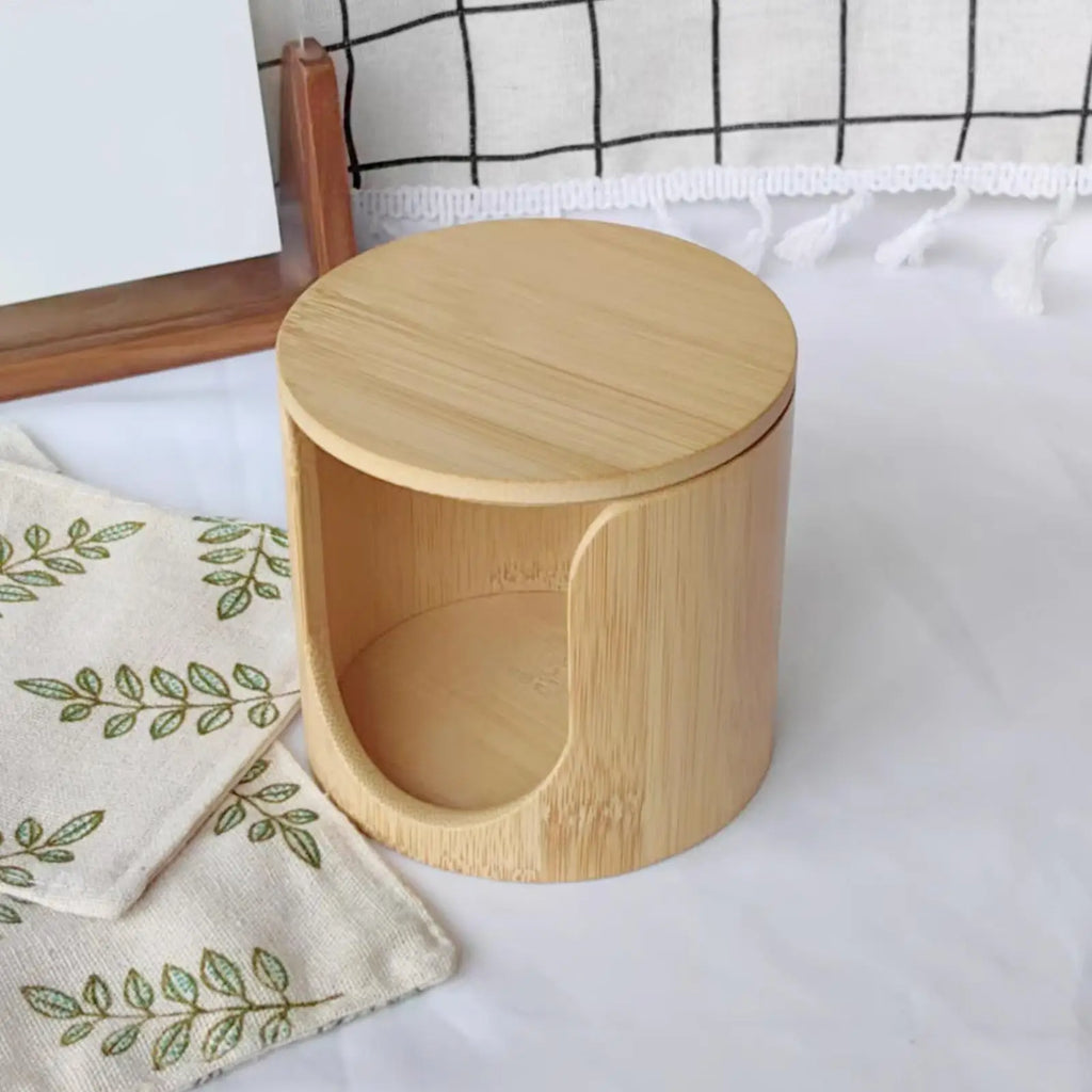 Empty bamboo cotton pad storage container with lid on a soft white surface