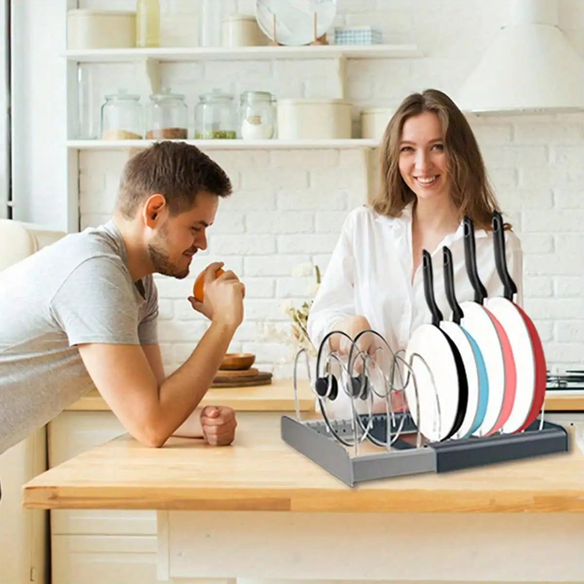 Expandable pan organizer rack displayed on a kitchen counter with people nearby