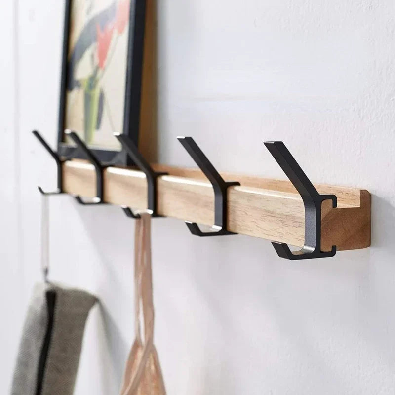 wall mounted oak coat rack with five black aluminum hooks holding a picture and hanging bags