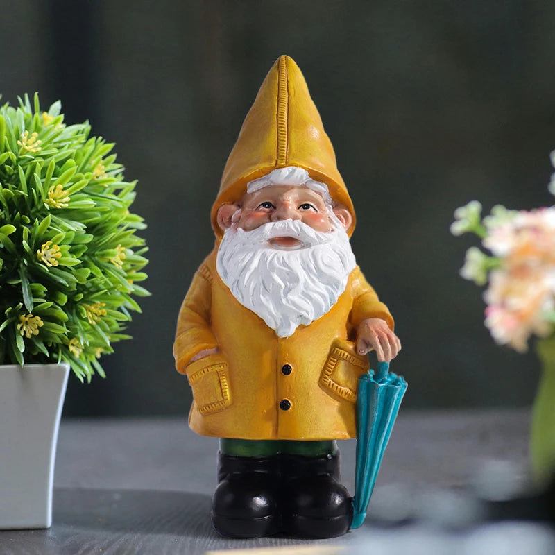 Resin garden gnome statue in yellow raincoat with blue umbrella on tabletop near plants