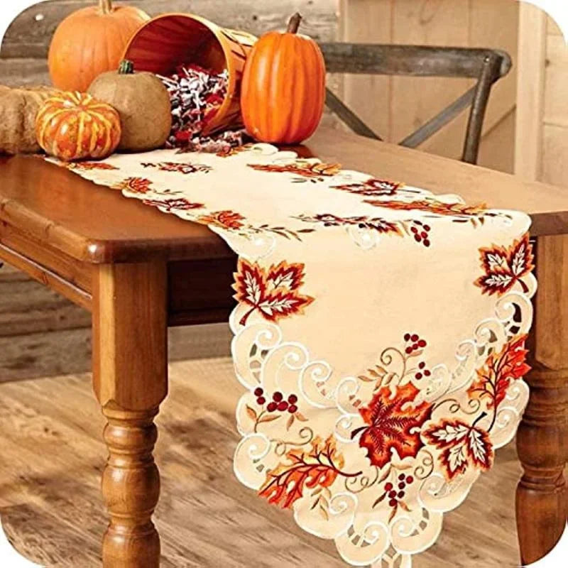 Maple leaf embroidered fall table runner on a wooden dining table with autumn pumpkins