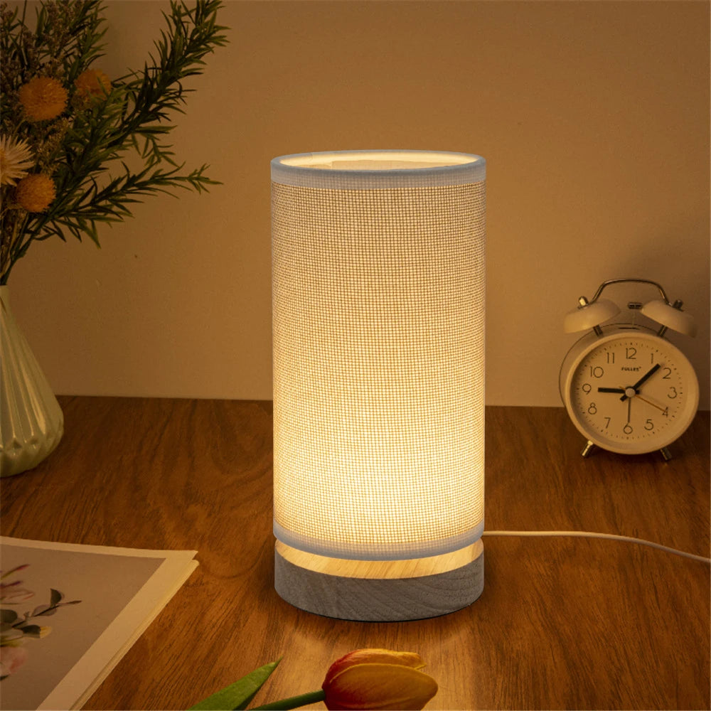 Cylindrical fabric shade LED lamp on a wooden desk with clock and decor