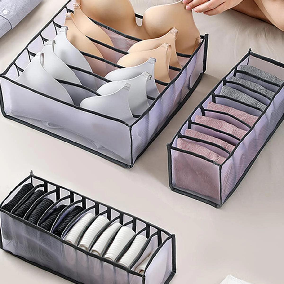 Foldable drawer organizers storing bras, socks, and underwear on a bed