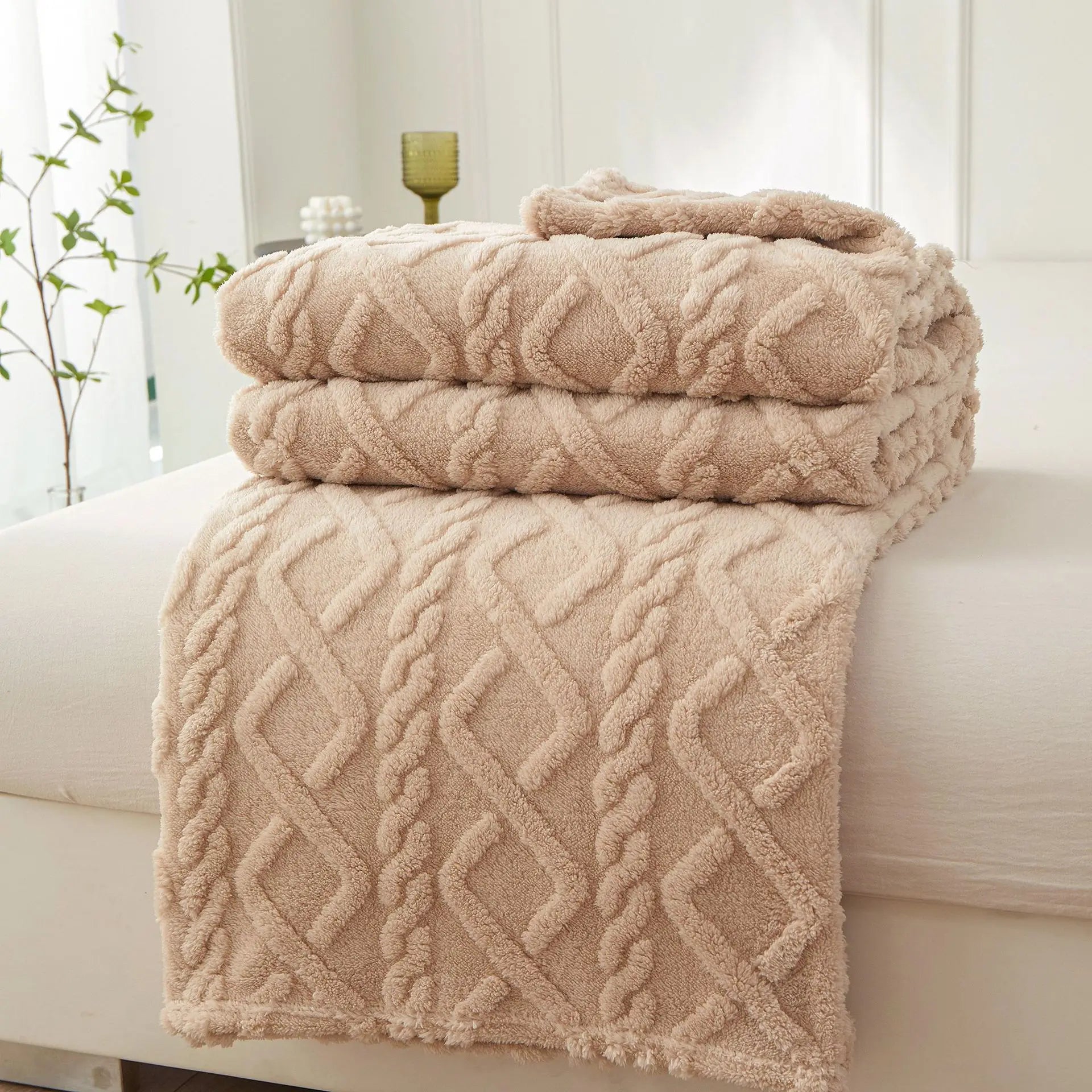 Braided sherpa fleece blanket folded on a bed in neutral beige, showing textured pattern