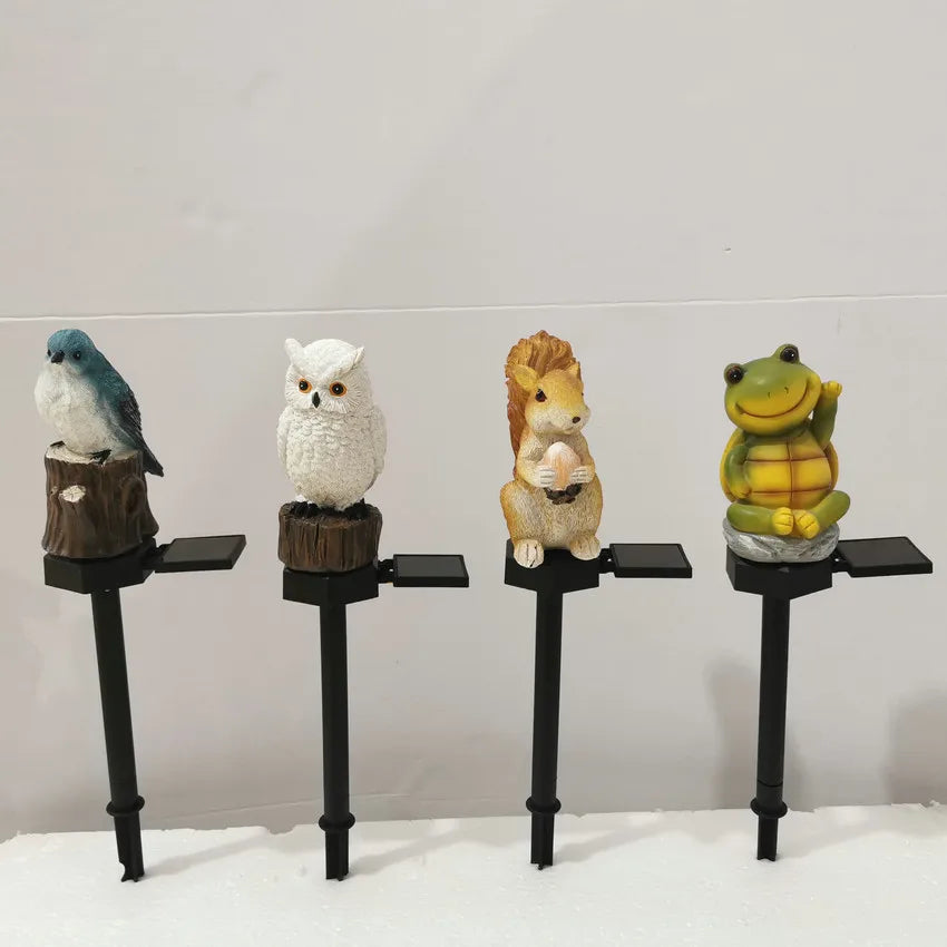 Four animal solar garden lights (bird, owl, squirrel, frog) on white background showing each figurine design