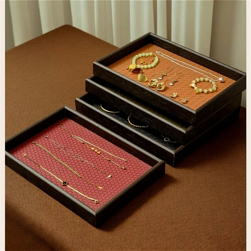 Rectangular faux leather trays with wood frame holding jewelry and bracelets on a tabletop