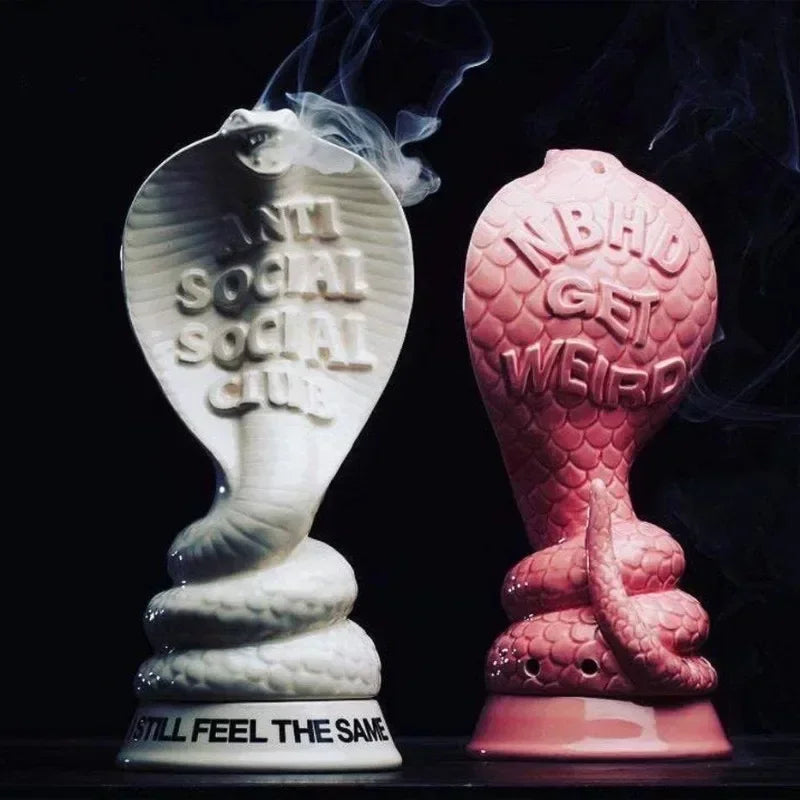 Cobra incense holders in pink and white in use with incense smoke rising
