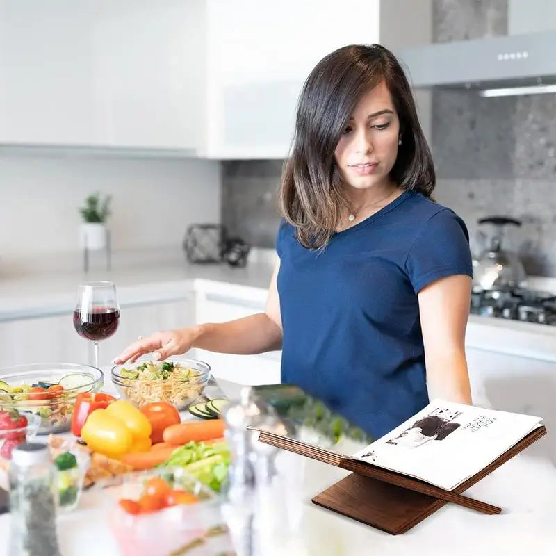 person cooking in a kitchen with a wooden book stand displaying a cookbook