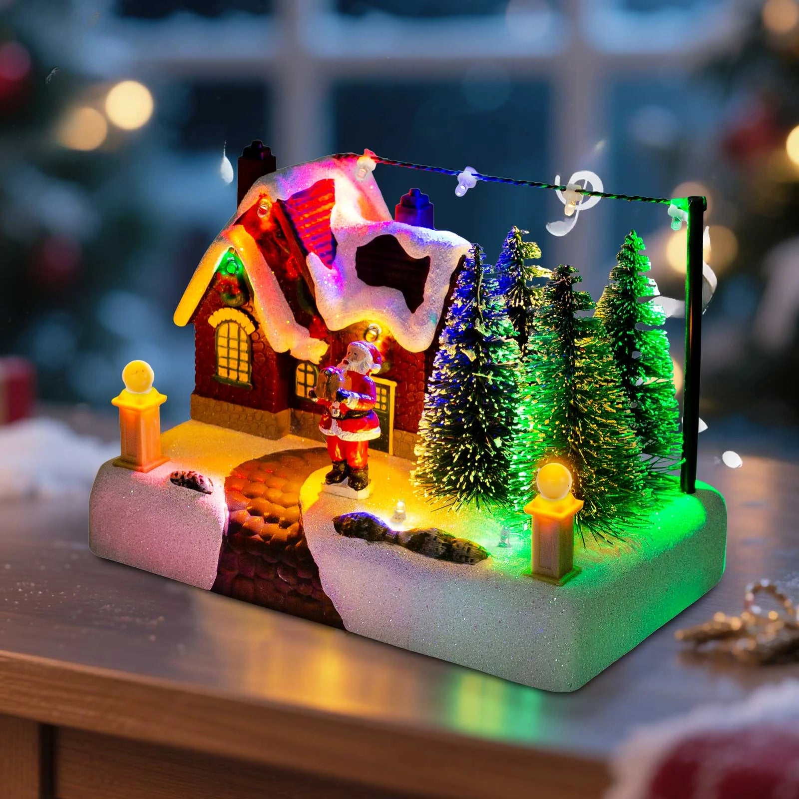 Close-up of battery operated Christmas village scene with lit house, Santa, and colorful trees