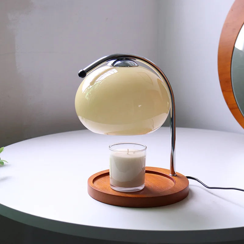 Candle warmer lamp with cream color shade and unlit jar candle on wooden base in daylight