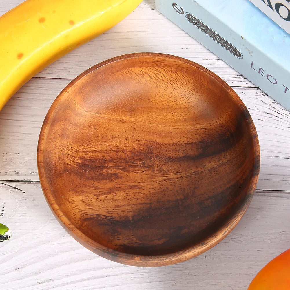 Small round wood snack bowl on a whitewashed table by fruit and a book