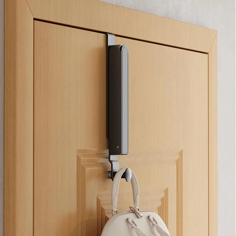 folded over-the-door drying rack hanging on a wooden door with a bag on the lower hook