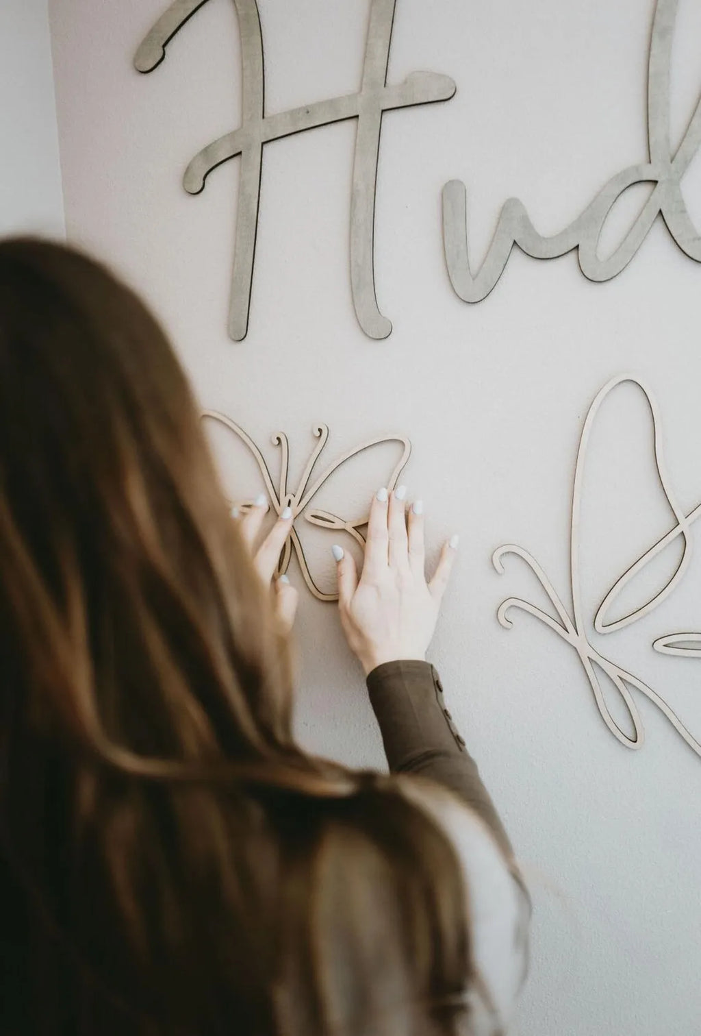 Person placing a lightweight wooden butterfly wall accent onto a painted wall