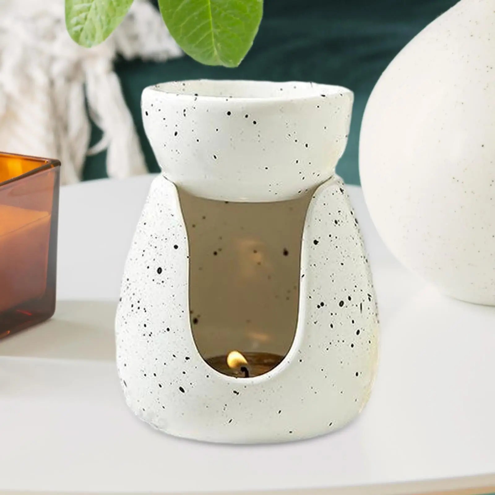 Ceramic essential oil burner on a side table with candlelight, home decor in background