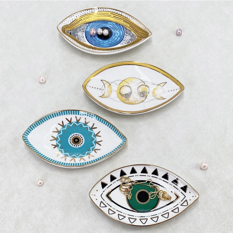 Four assorted eye-patterned ceramic jewelry trays with rings and pearls