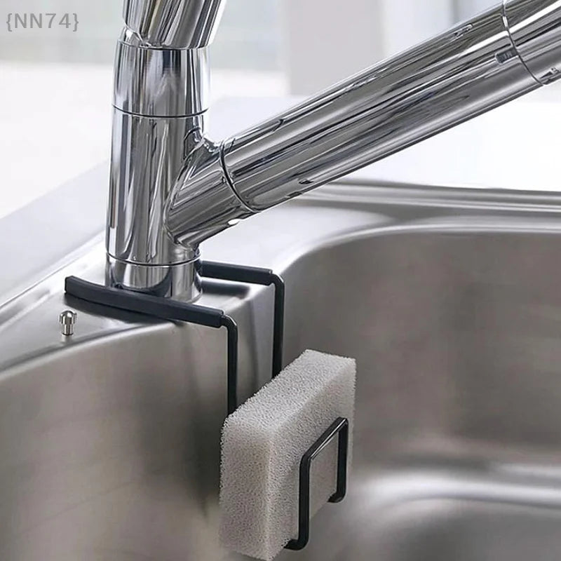 Black metal faucet caddy with sponge attached to a sink