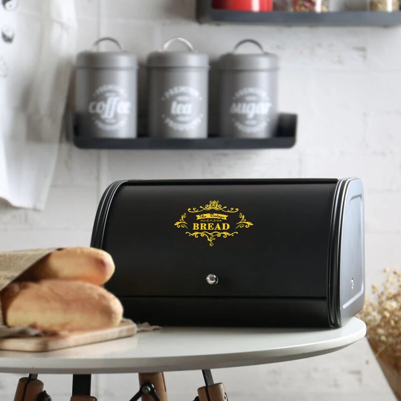 Black clamshell metal bread box in a kitchen with canisters in the background