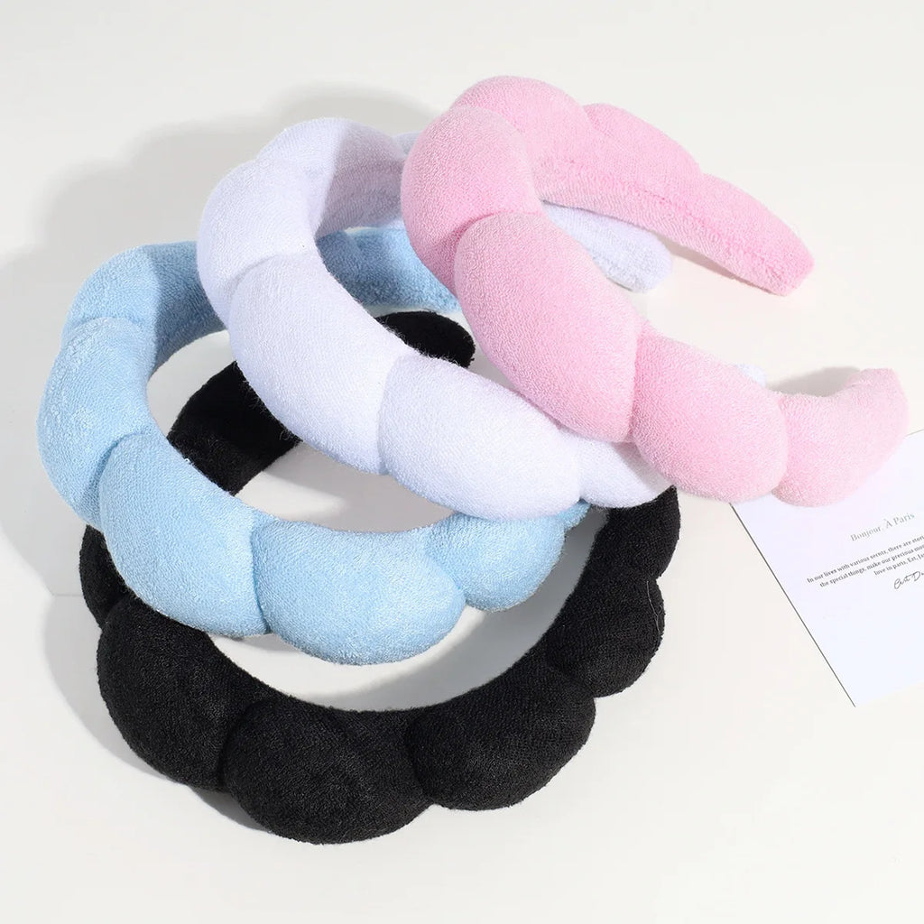 three padded headbands in blue, pink, and black stacked together on a white background