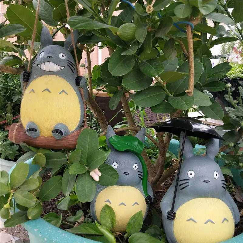 Three resin forest animal statues with swing, leaf, and umbrella, tucked in a large potted plant