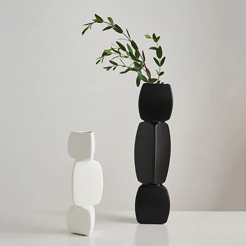 Black and white sculptural ceramic vases, tall geometric design, with greenery