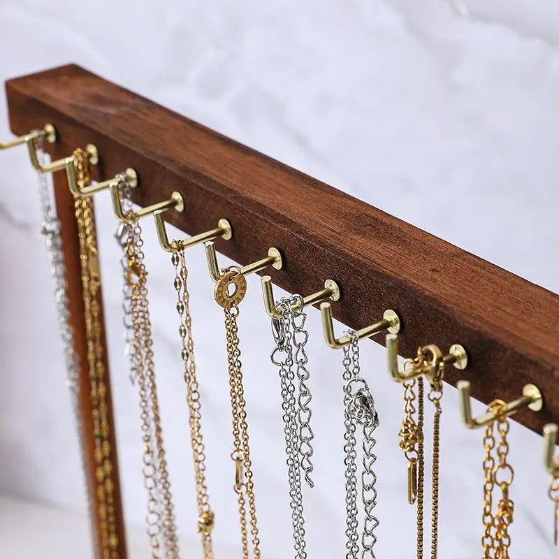 close-up of metal hooks on a wood jewelry organizer displaying chain necklaces