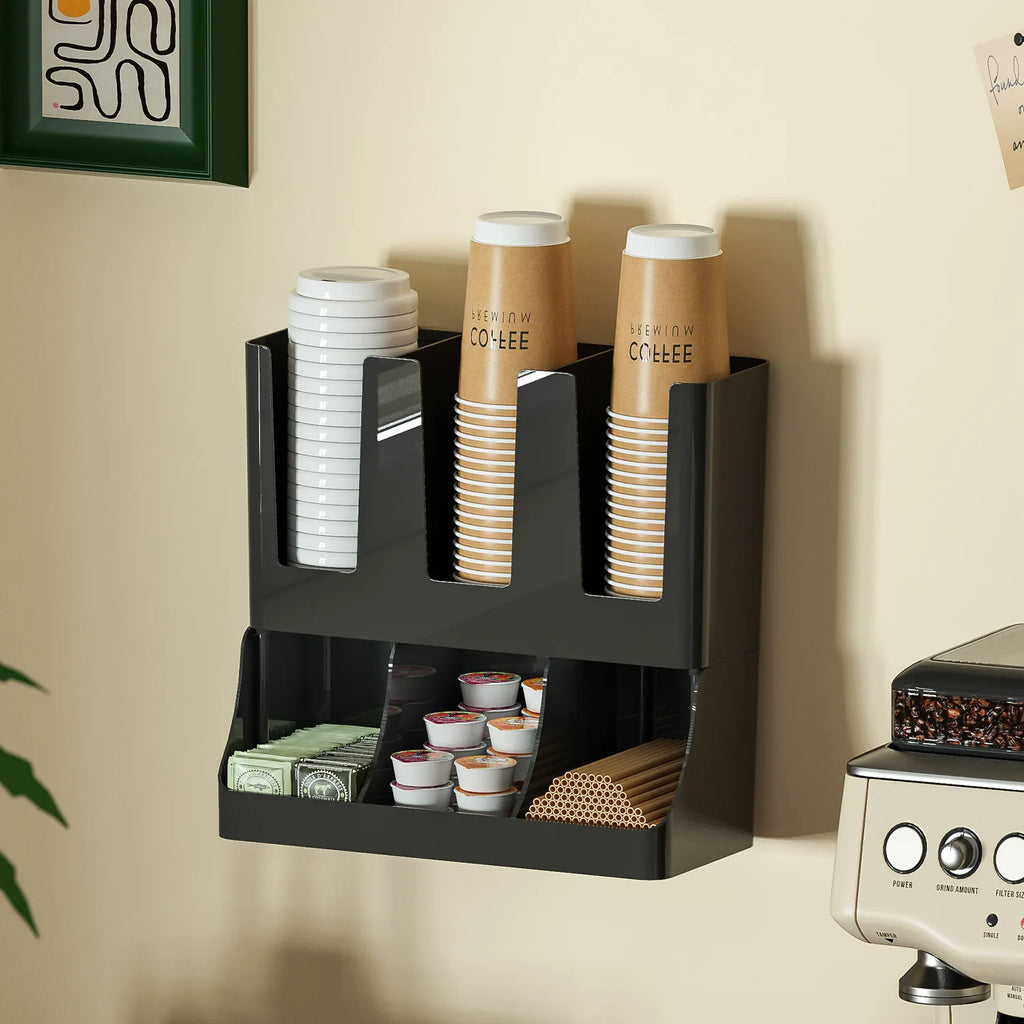 Black wall-mounted coffee station organizer hung above a countertop, holding cups, lids, pods, and stirrers beside a coffee maker.