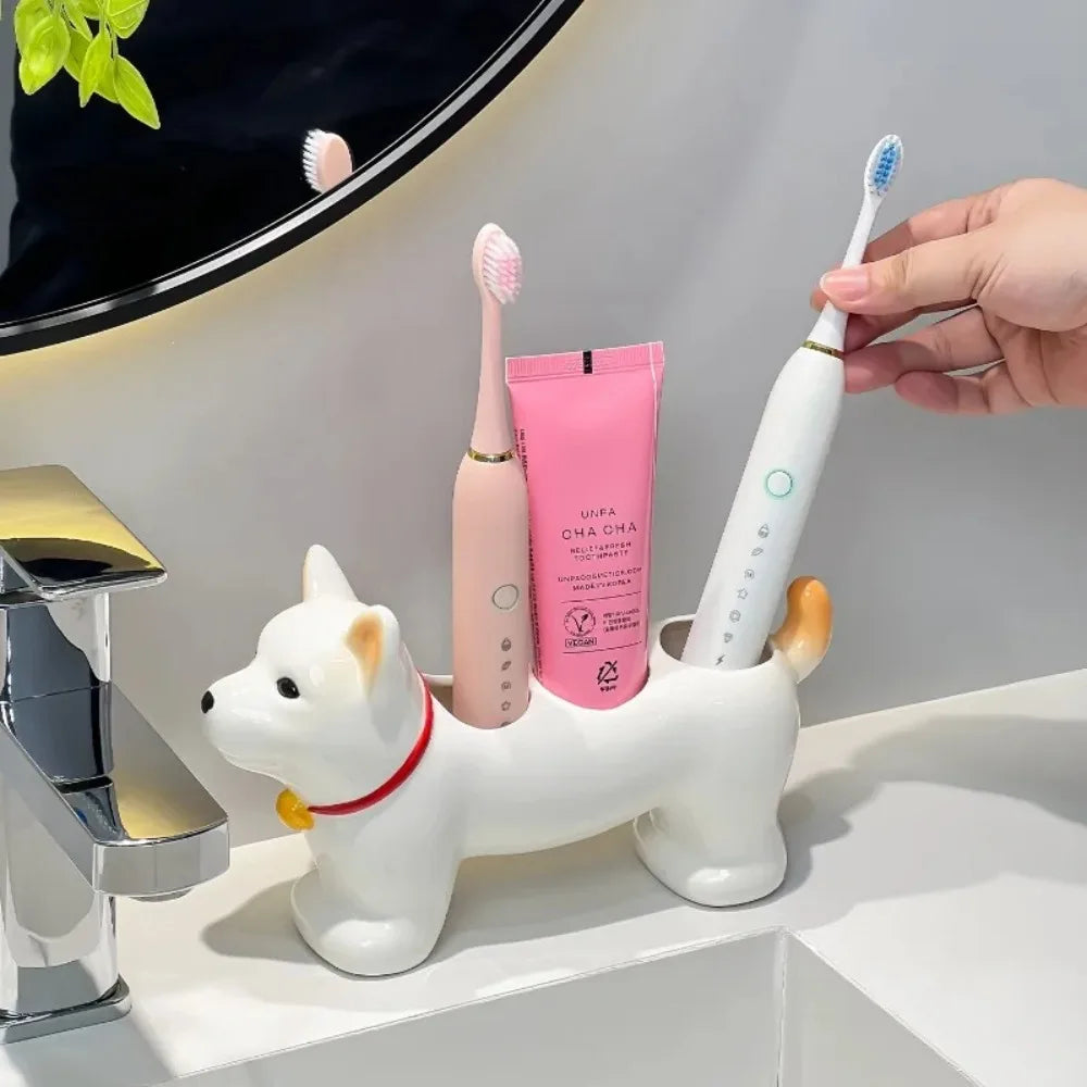White dog-shaped ceramic toothbrush holder on sink, holding two electric toothbrushes and a pink toothpaste tube