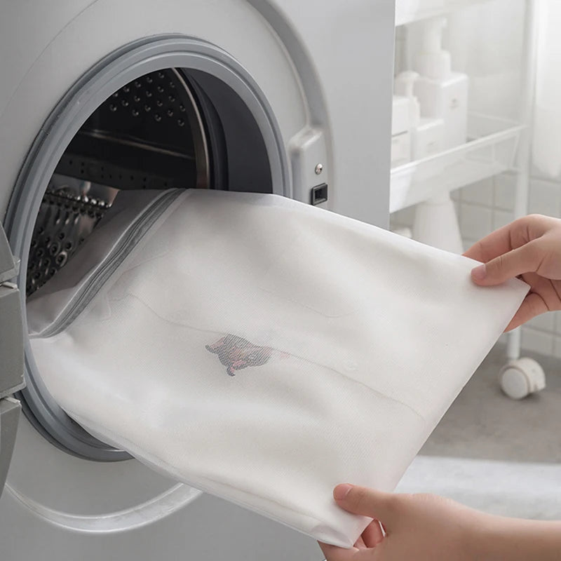 Mesh laundry bag with zipper being placed inside a washing machine