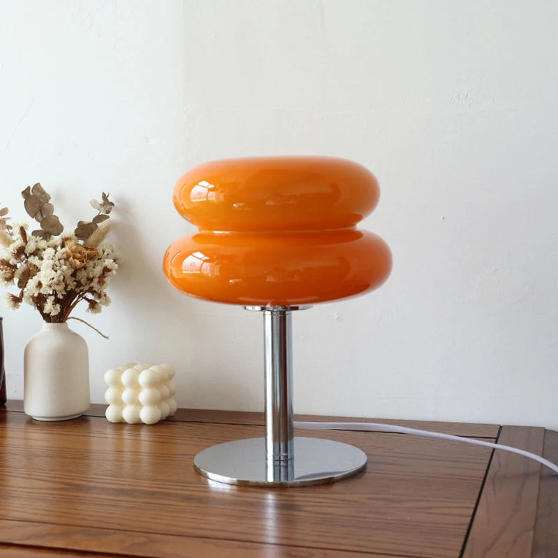 Orange macaron glass table lamp on a wood nightstand with neutral decor