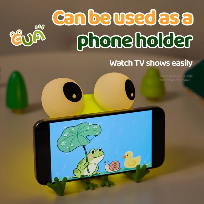 Frog silicone night light used as a phone stand, holding a smartphone horizontally