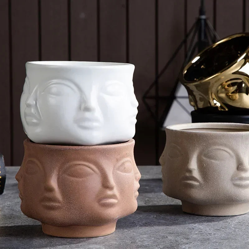 Three sculptural ceramic vases with embossed face designs in white, natural, and beige tones