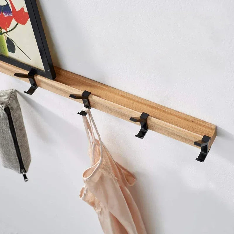 top view of wall mounted oak coat rack with five movable hooks and items hanging from it