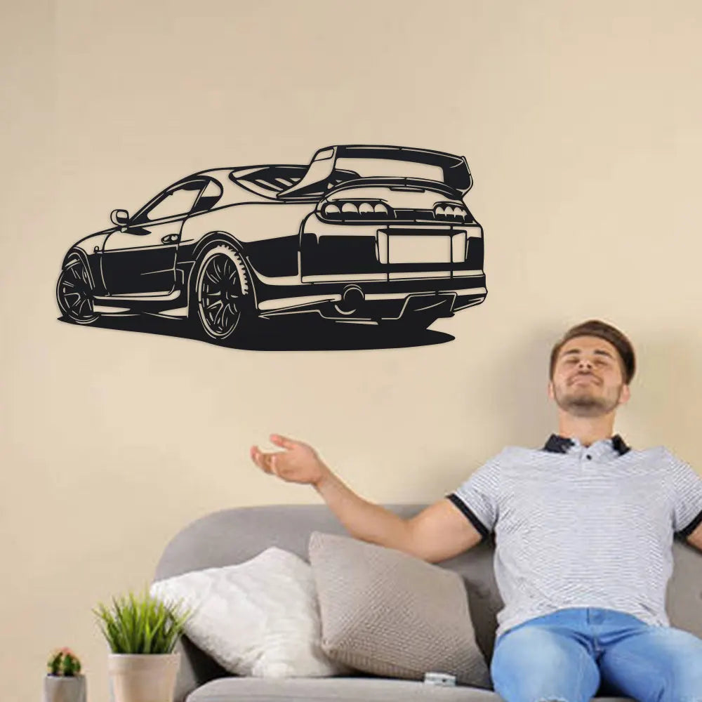 Black metal car silhouette art displayed above a gray sofa with a man relaxing