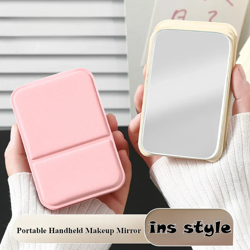 Two hands holding a pink and a beige foldable PU leather makeup mirror, front and back views