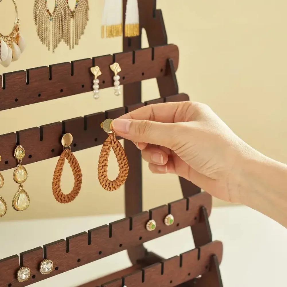 hand placing a woven teardrop earring onto the wooden earring rack