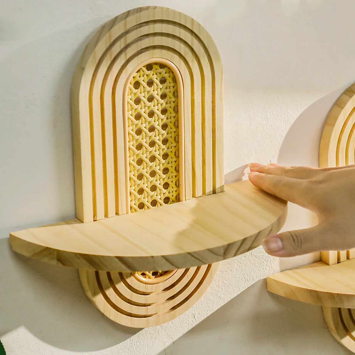 closeup of hand showing the floating shelf's sturdy wooden construction and rattan accent back