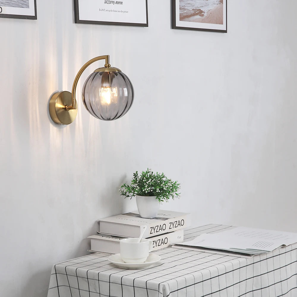 Smoke gray glass ribbed wall sconce with brass mount above a dining or study table