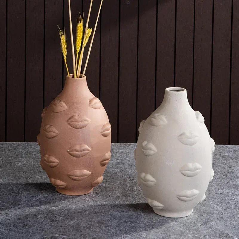 Egg-shaped ceramic vases with embossed lips design in beige and terracotta, displayed on a table