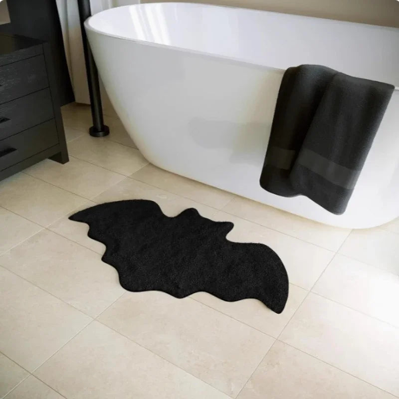 Bat shaped non-slip floor rug by a white bathtub with dark towels, styled for fall