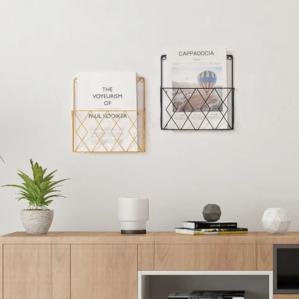 Entryway or home office setup with black and gold magazine racks mounted on the wall above a console table, holding papers.